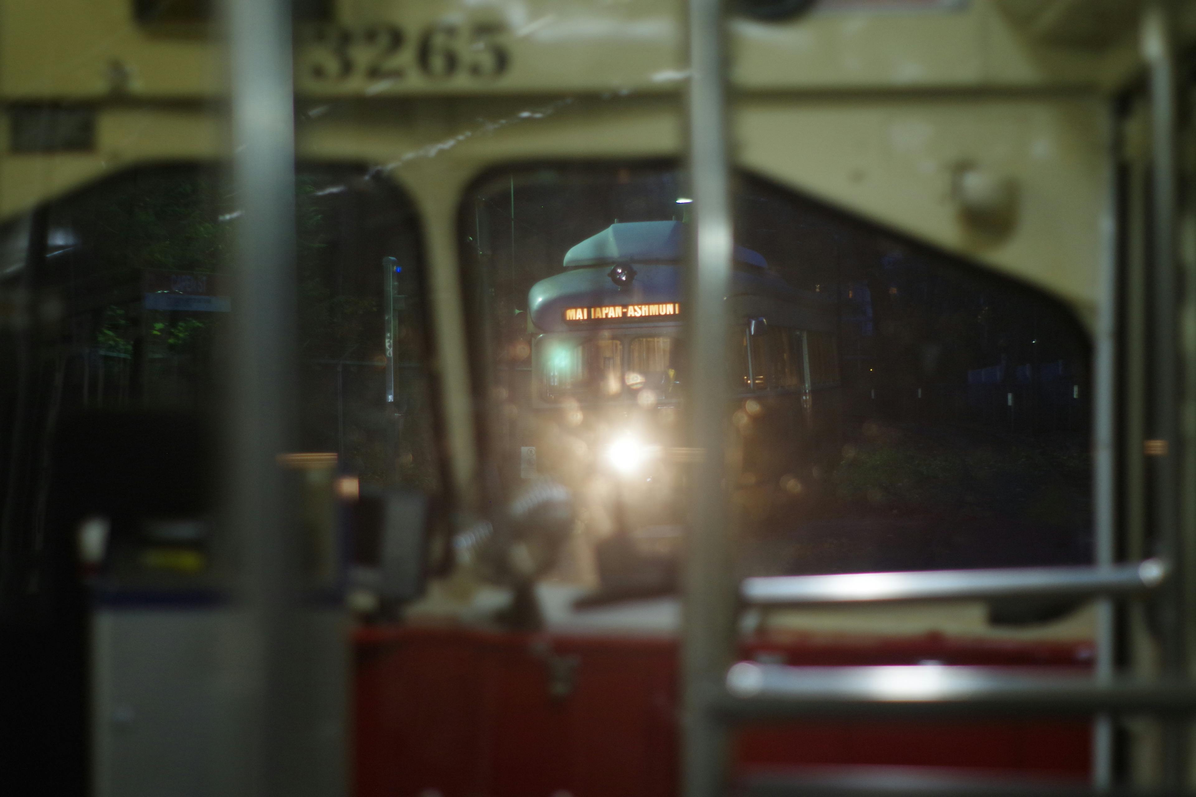 looking out the front of a PCC streetcar on the MBTA's Mattapan Line in Boston at night, at another oncoming streetcar