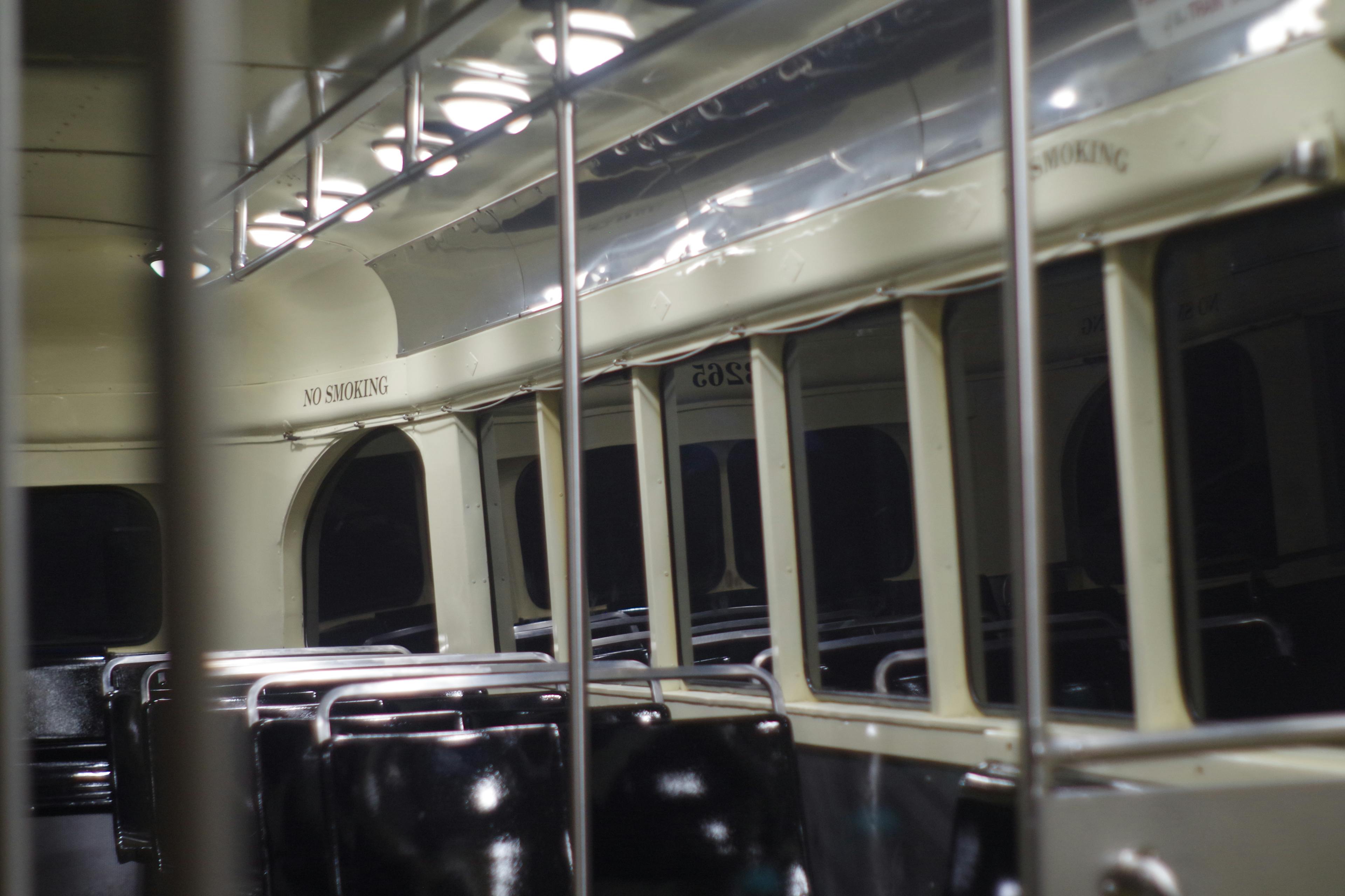 a view of the rear of the same streetcar, with darkness visible in the windows and rows of transverse seating inside the car