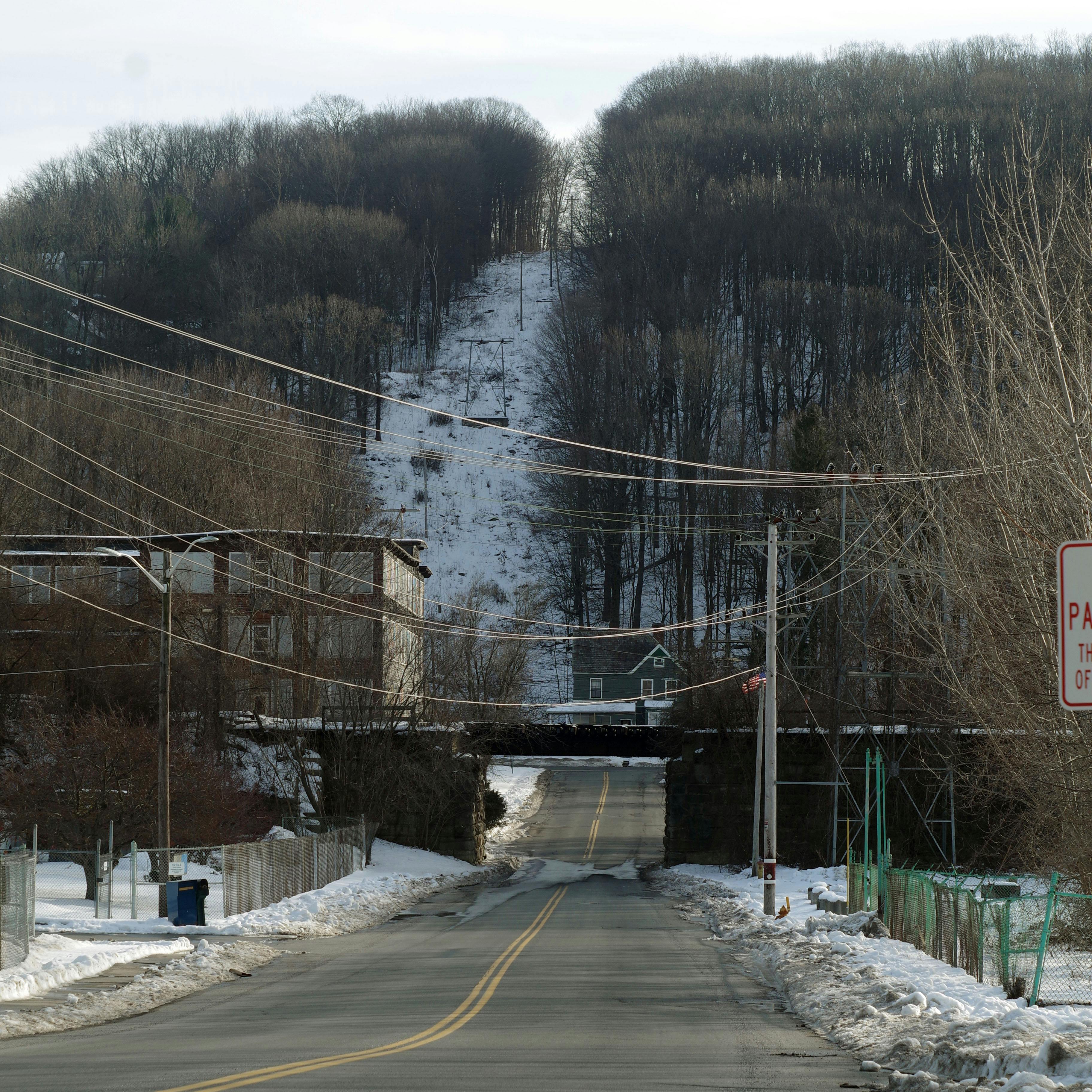 looking down a road, under a railroad bridge, and up at a power line path cut into a hill
