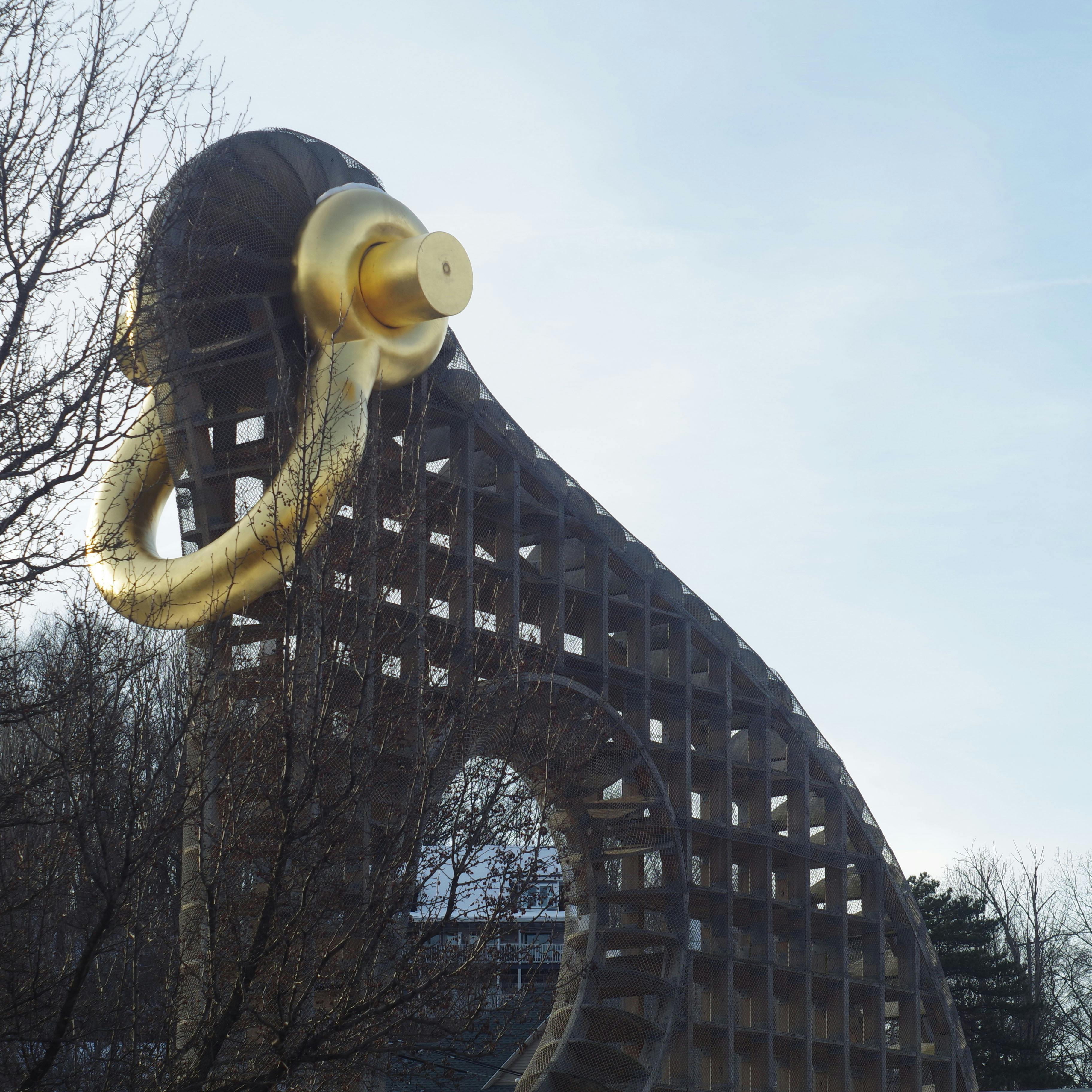an odd sculpture featuring a concrete lattice and a gold beam